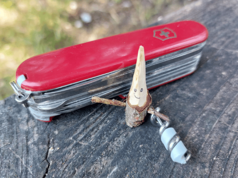 mittleres taschenmesser huntsman rot mit geschnitzer holzfigur im wald