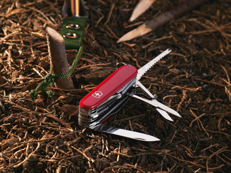 mittleres taschenmesser swiss champ rot auf waldboden vor zelt zum campen verwenden
