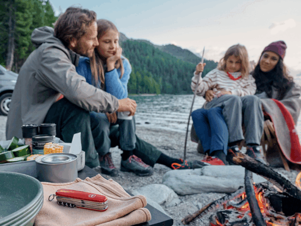 familie beim camping am lagerfeuer mit einem taschenmesser