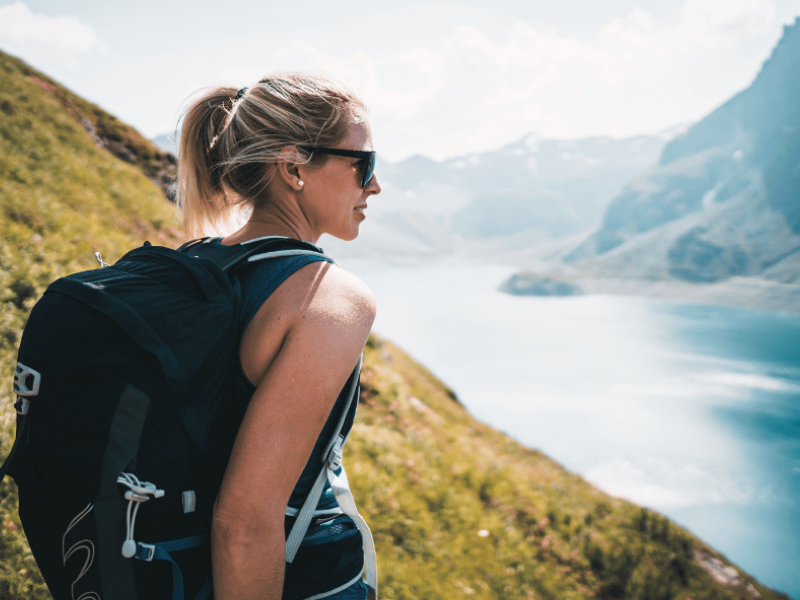 frau beim wandern am berg mit blick auf einen see