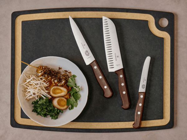 kochmesser holz wood kollektion auf schwarzen schneidbrett und daneben eine schüssel mit ramen zutaten