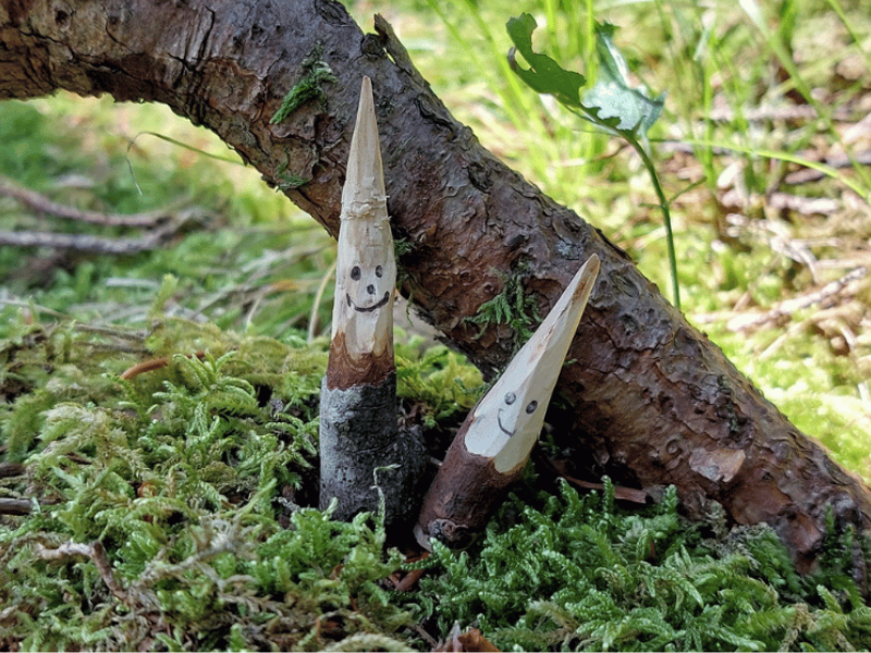 Geschnitzte Holzwichtel mit Gesicht im Wald
